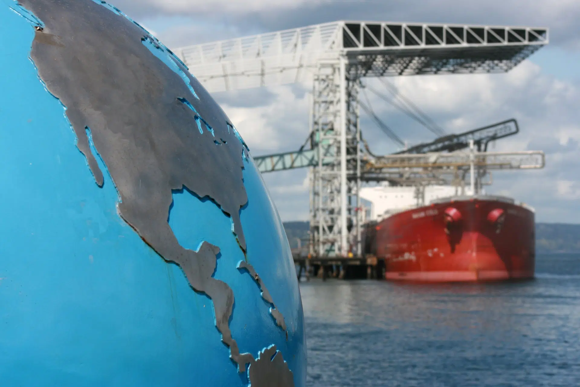 An image of a globe and a cargo ship in the distance