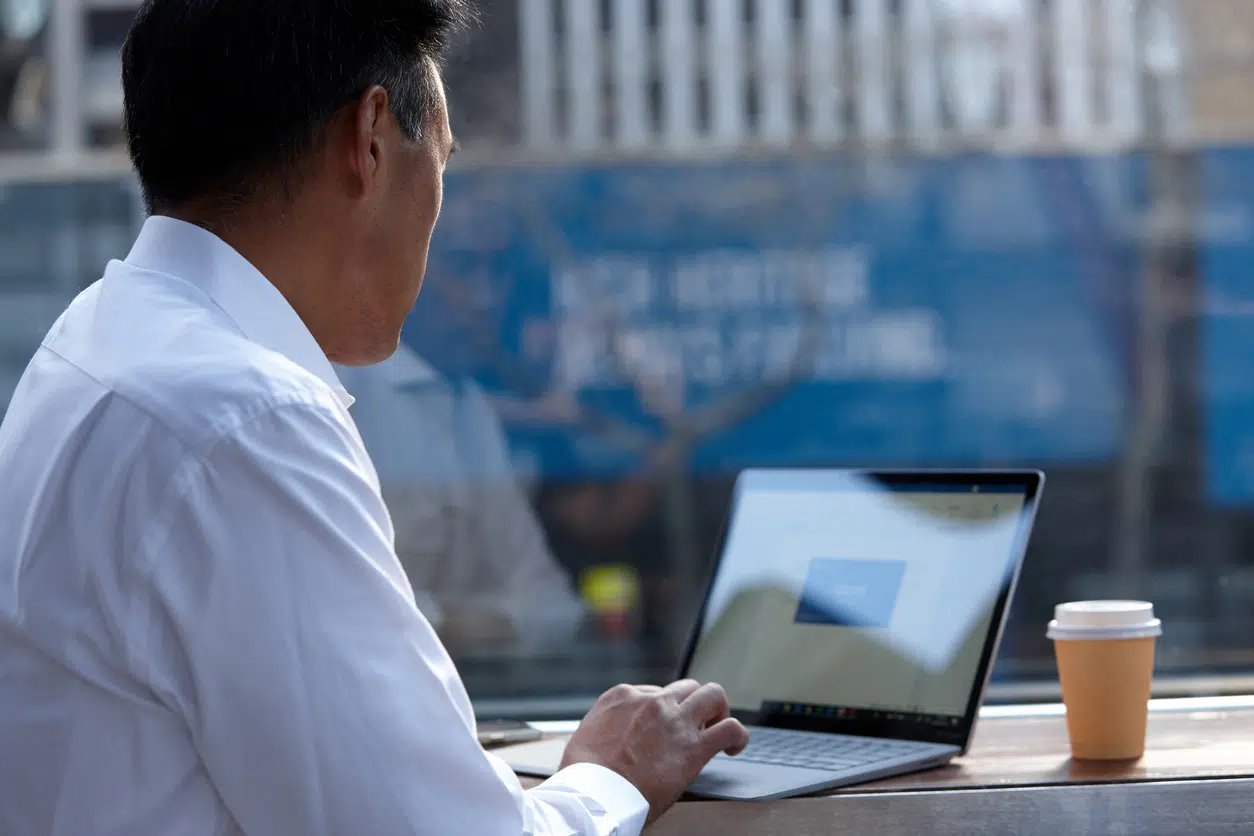 Australasian businessman working on laptop outside